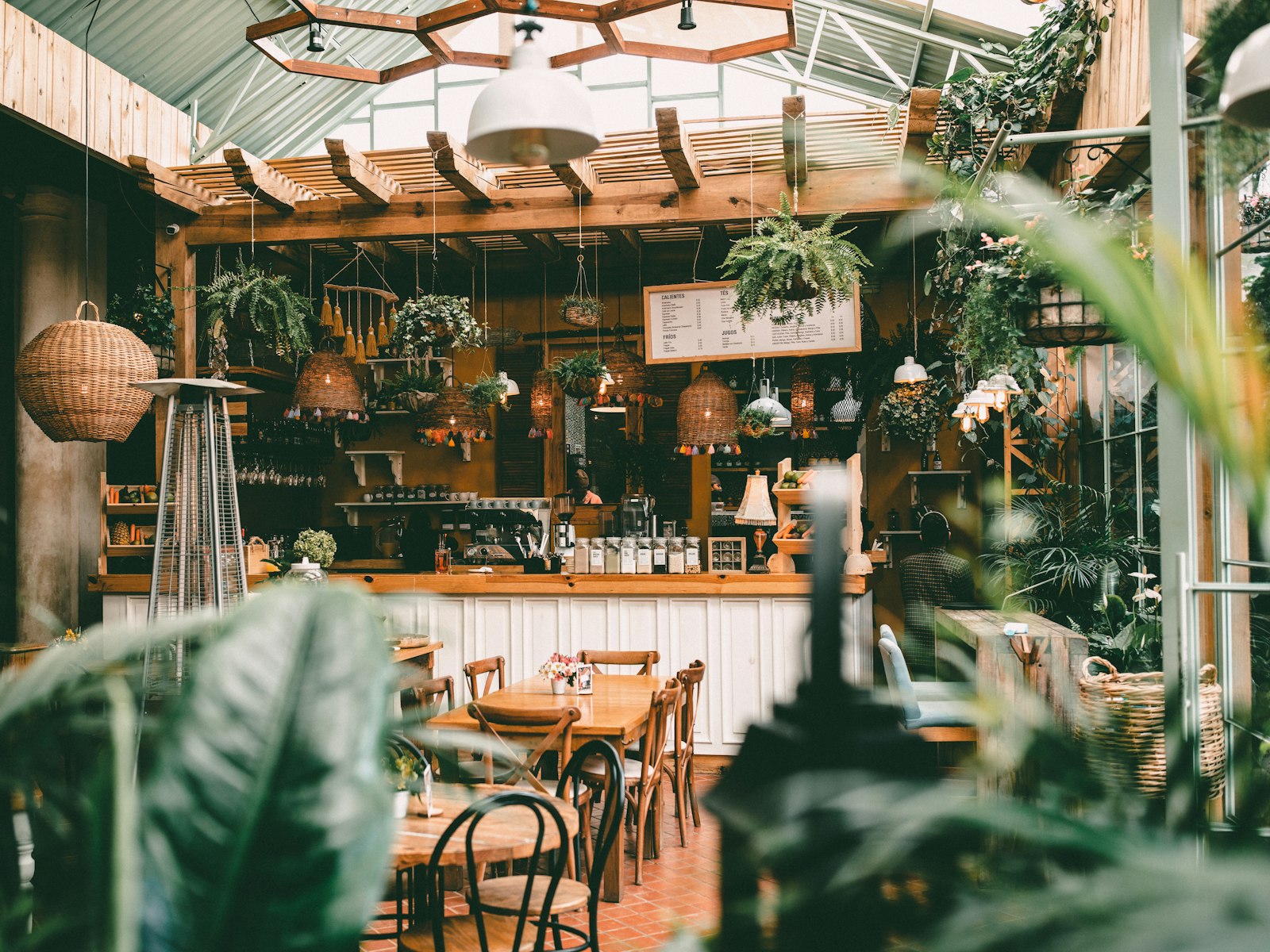 A bright café room with plants and small tables