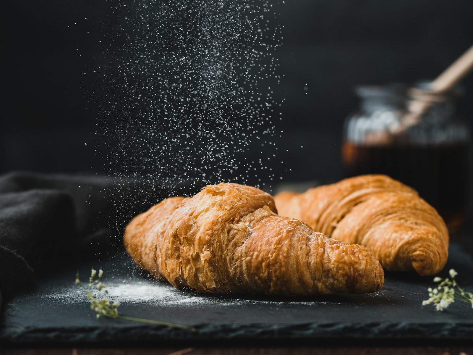 A croissant being dusted with sugar